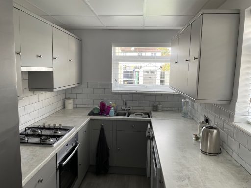 Modern grey kitchen renovation by Pro Home Services in Croydon, featuring sleek fitted cabinets, white tiled backsplash, light worktops
